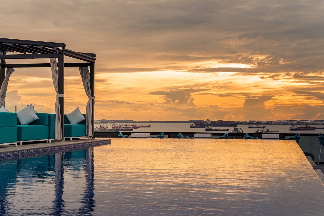 A sunset view from the infinity pool at 1-Altitude Coast, the rooftop entertainment venue at The Outpost Hotel Sentosa. 